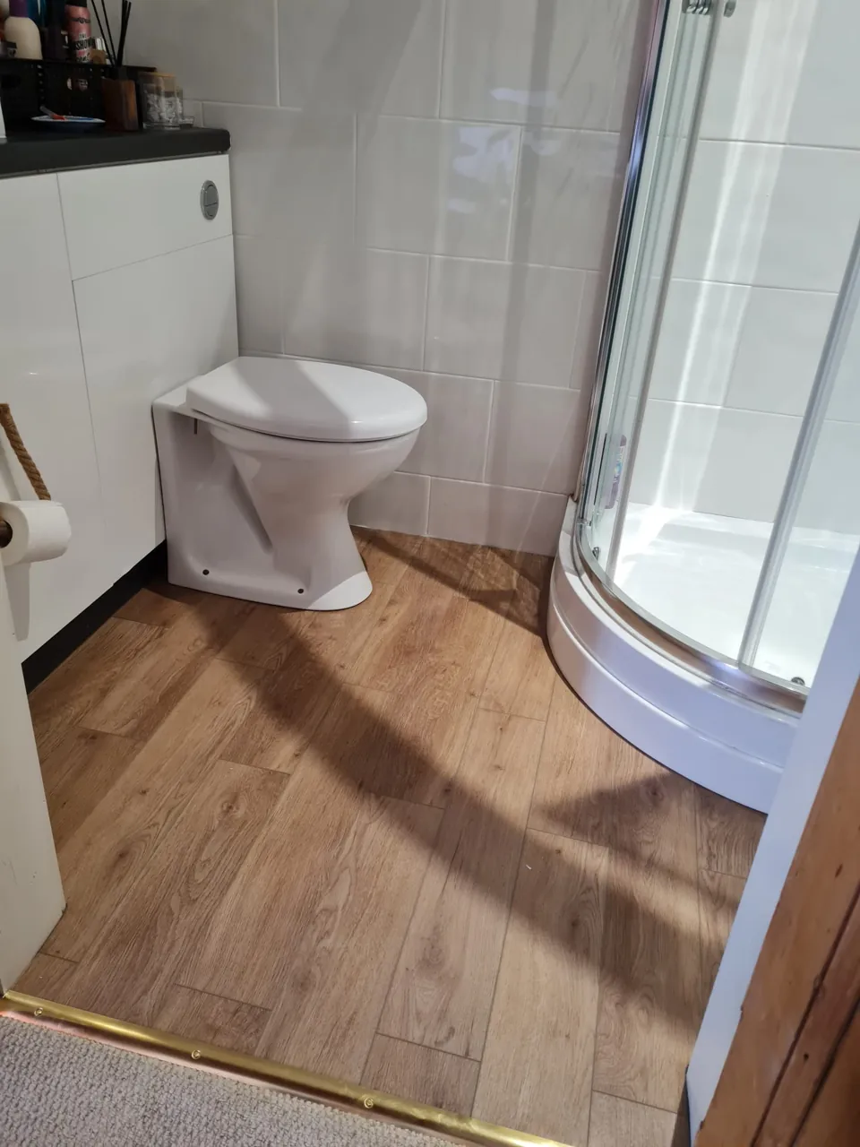 Curved shower tray, toilet and wood-effect bathroom floor