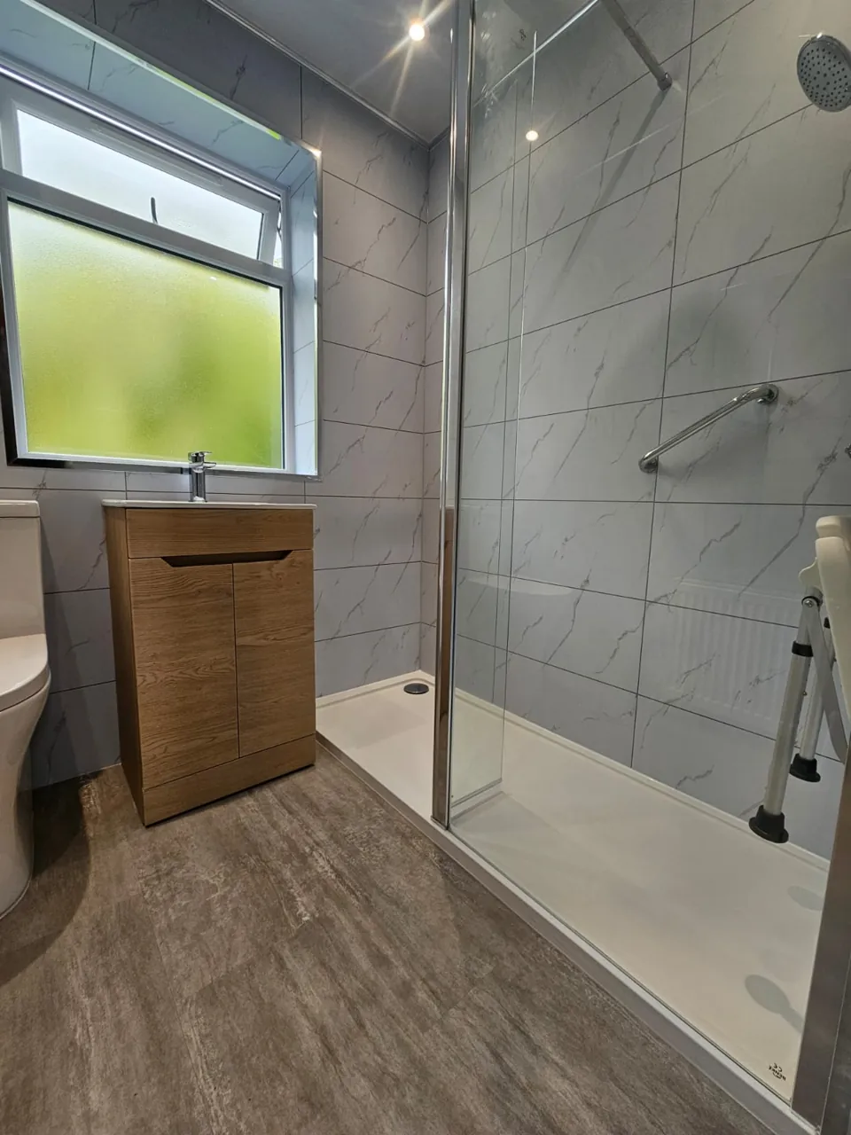 Compact shower room with oak vanity and marble-effect walls